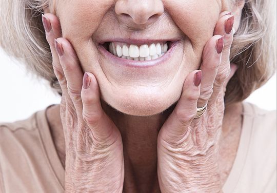 Patient cupping both sides of her face due to denture pain before receiving treatment at Dr. James A. Vette, DDS in Germantown, MD